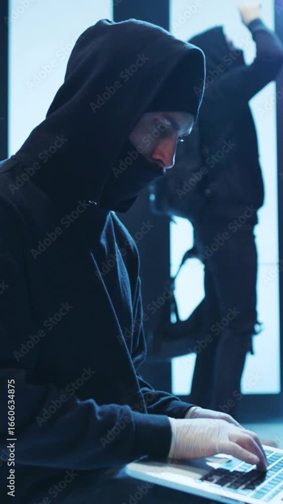 Aufkleber a mysterious hacker is working intensely on a laptop in a dark, shadowy setting