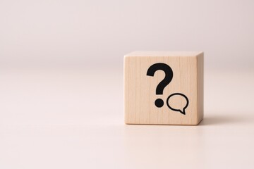 Wooden Block Displaying Question Mark and Speech Bubble Graphic Against a Neutral Background