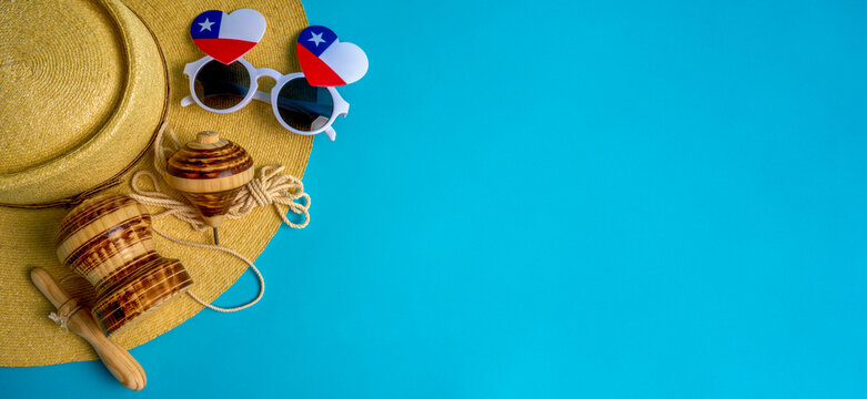 Traditional chilean wooden spinning top, embu, with huaso hat and chilean flag sunglasses celebrating chilean festivities on turquoise background