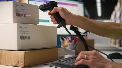 Logistics hub worker uses scanner on tracking info tags for express delivery, conducting order fulfillment for cargo goods distribution. Parcel tracking and barcode scanning, e commerce. Camera A.