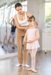 During ballet training, teacher corrects student, teaches her to keep posture correctly and...