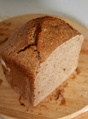 Homemade dark whole grain wheat sourdough bread, baked in a bread machine, on a cutting board. A modern and healthy baking result.