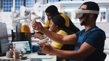 African american technician in solar panels plant using VR goggles, optimizing layouts using CAD software. Photovoltaics factory worker using virtual reality tech to do arrangements. Camera A.