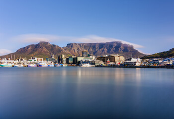 Fototapeta premium Wide angle long exposure of V and A Waterfront and Table Mountain with blue sky, Cape Town, South Africa