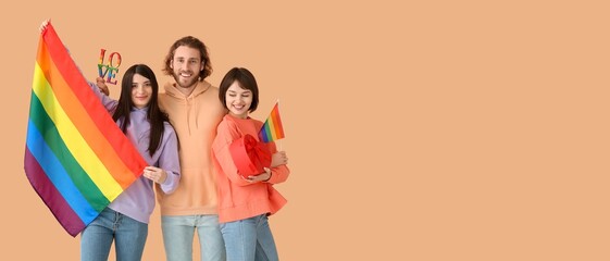 Man and two women with LGBT flags, gift and word LOVE on beige background with space for text