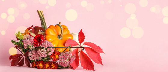 Basket with Halloween pumpkins and beautiful flowers on pink background