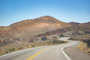 Empty desert highway stretches into hazy mountains under a clear sky