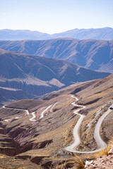 Empty desert highway stretches into hazy mountains under a clear sky