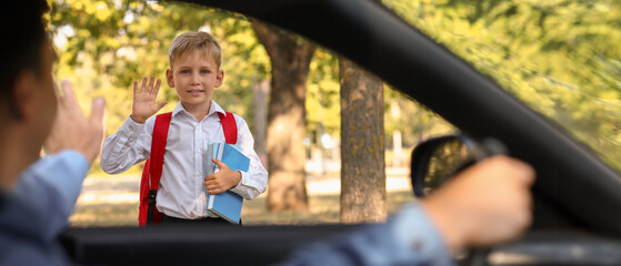 Father waving hand to his son near school, view from inside the car