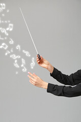 Hands of young female conductor on grey background