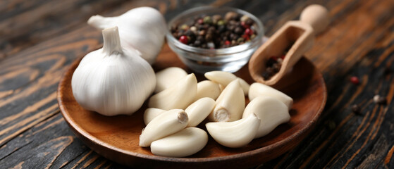 Plate with fresh garlics and peppercorns on wooden background, closeup