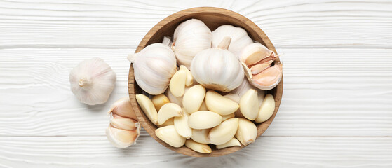 Bowl with fresh garlics on white wooden background