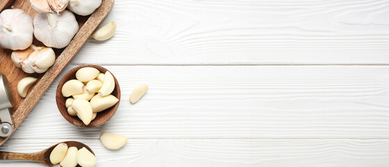 Tray with fresh garlics and bowl of cloves on white wooden background