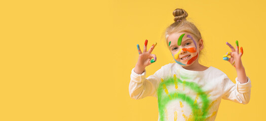 Cute little girl in paint on yellow background
