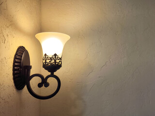 Vintage wall lamp glowing softly on textured plaster wall