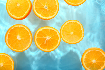 Slices of fresh orange in water on blue background