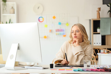 Female interior designer working with graphic tablet at table in office