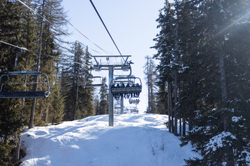 Cable car or fanicular moving against the background of winter forest, snow-covered mountains and...