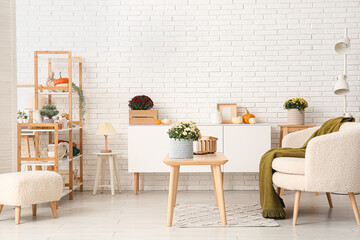 Interior of stylish living room with white sofa and chrysanthemum flowers on coffee table