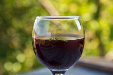 Black blackberry wine in a glass on a wooden table
