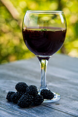 Black blackberry wine in a glass on a wooden table