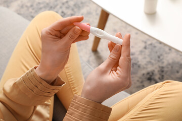 Woman with pregnancy test at home, top view