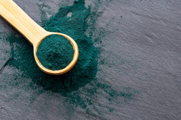 Organic green spirulina powder in a spoon - Nutritional supplement.