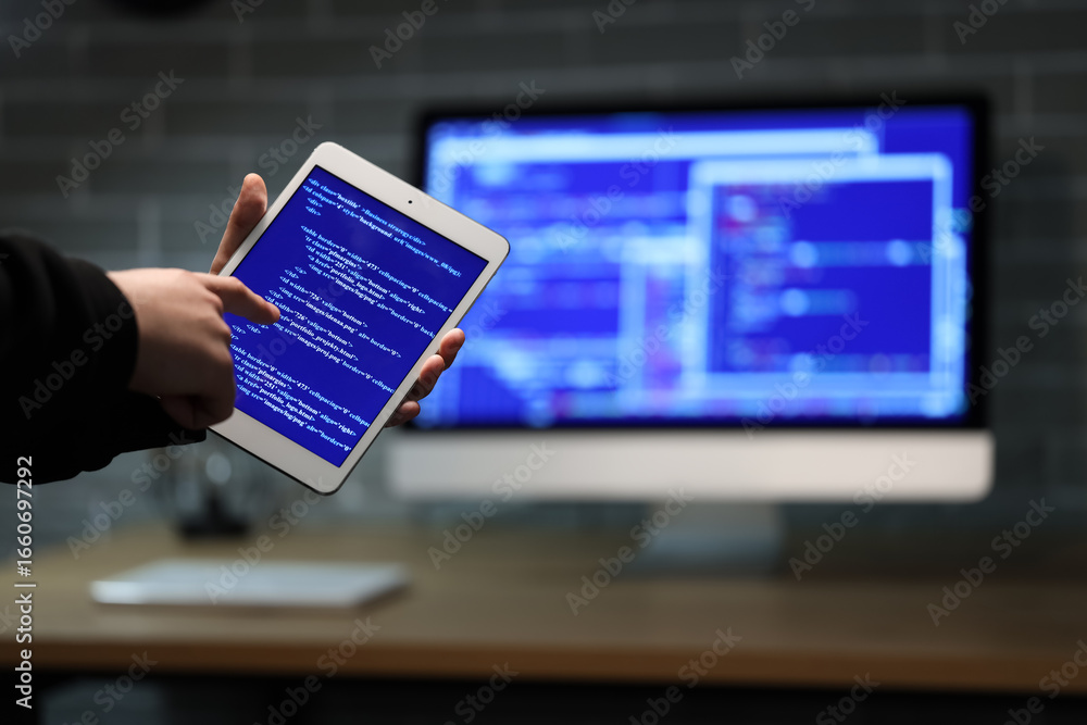 Aufkleber hacker using tablet computer in dark room, closeup