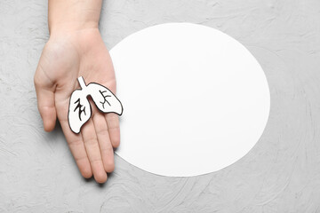 Female hand with paper lungs and blank card on grey background