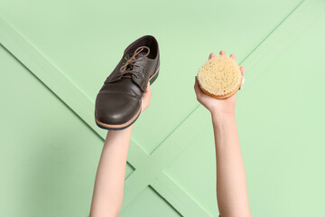 Female hands with shoe and brush on green wooden background. Shoes repair concept
