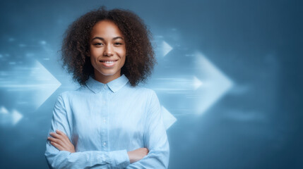 Fototapeta na wymiar Confident young woman with curly hair smiles while standing with her arms crossed. She wears light blue button up shirt against blurred background with dynamic arrows, conveying sense of progress