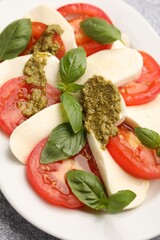 Tasty salad Caprese with mozzarella, tomatoes, basil and pesto sauce on table, closeup