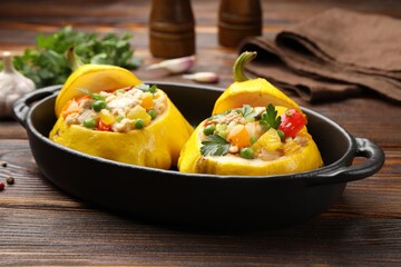 Tasty stuffed pattypan squashes in baking dish on wooden table, closeup