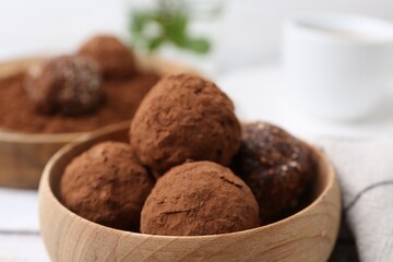 Delicious homemade candies with cocoa powder in bowl on table, closeup