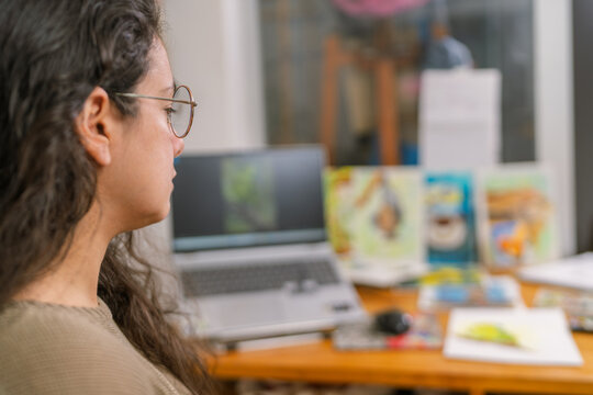 Graphic designer working from home on laptop in creative workspace - Powered by Adobe