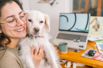 Graphic designer hugging her dog while working from home