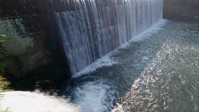 Water dam view in tropical countryside with bridge built structure. Waterfall close up view