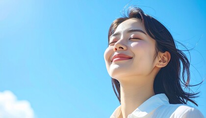 快晴の中で髪を風になびかせた若い日本人女性,A young Japanese woman with her hair blowing in the wind under a clear blue sky.	