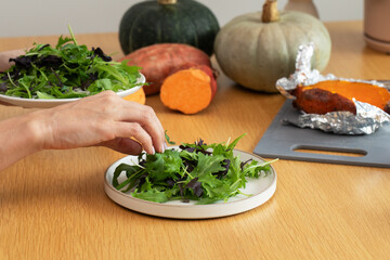 Fresh salad preparation with leafy greens and baked vegetables on table