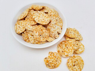 Tempeh chips in a white plate on a white background.