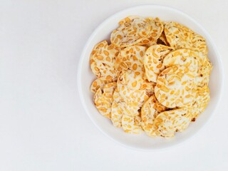 Tempeh chips in a white plate on a white background. 