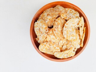 Tempeh chips in a wooden plate on a white background. Top of view. 