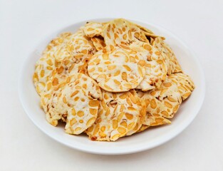 Tempeh chips in a white plate on a white background.