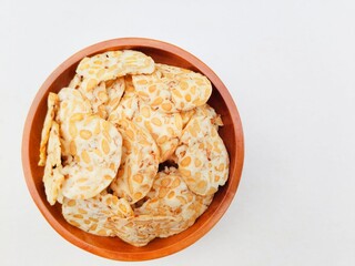 Tempeh chips in a wooden plate on a white background. Top of view. 