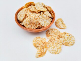 Tempeh chips in a wooden bowl on a white background. High angle view. 