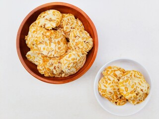 Tempeh chips in a small white plate and a wooden plate  on a white background. Top of view. 