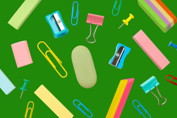 Various school supplies are scattered on a green background
