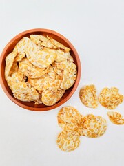 Tempeh chips in a wooden plate on a white background. Top of view. 