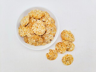 Tempeh chips in a white plate on a white background. Top of view. 