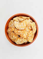 Tempeh chips in a wooden plate on a white background. Top of view. 